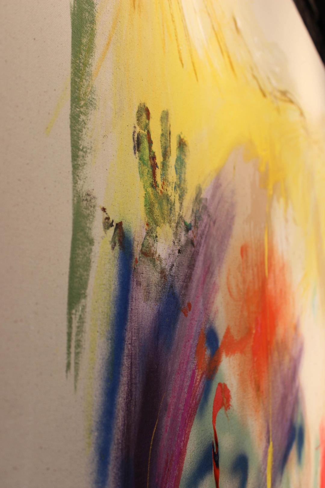 detail of a right hand print made in green paint on top of purple and yellow